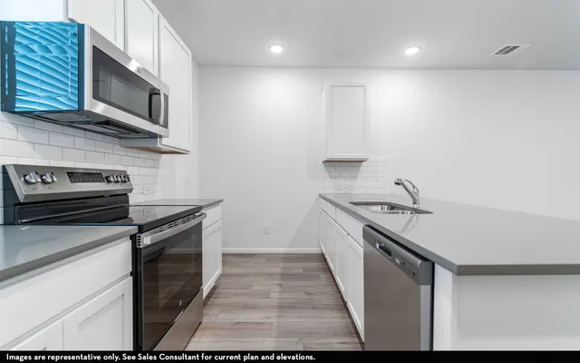 a kitchen with stainless steel appliances granite countertop a sink stove and microwave
