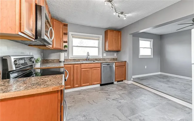 a kitchen with stainless steel appliances granite countertop a sink stove cabinets and wooden floor