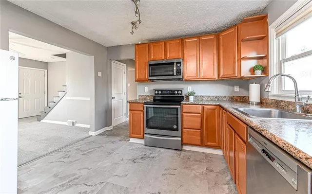 a kitchen with stainless steel appliances granite countertop a stove a sink and a refrigerator