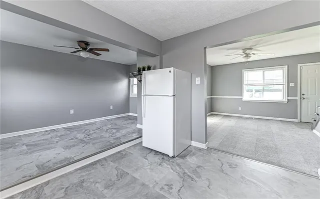an empty room with windows and refrigerator