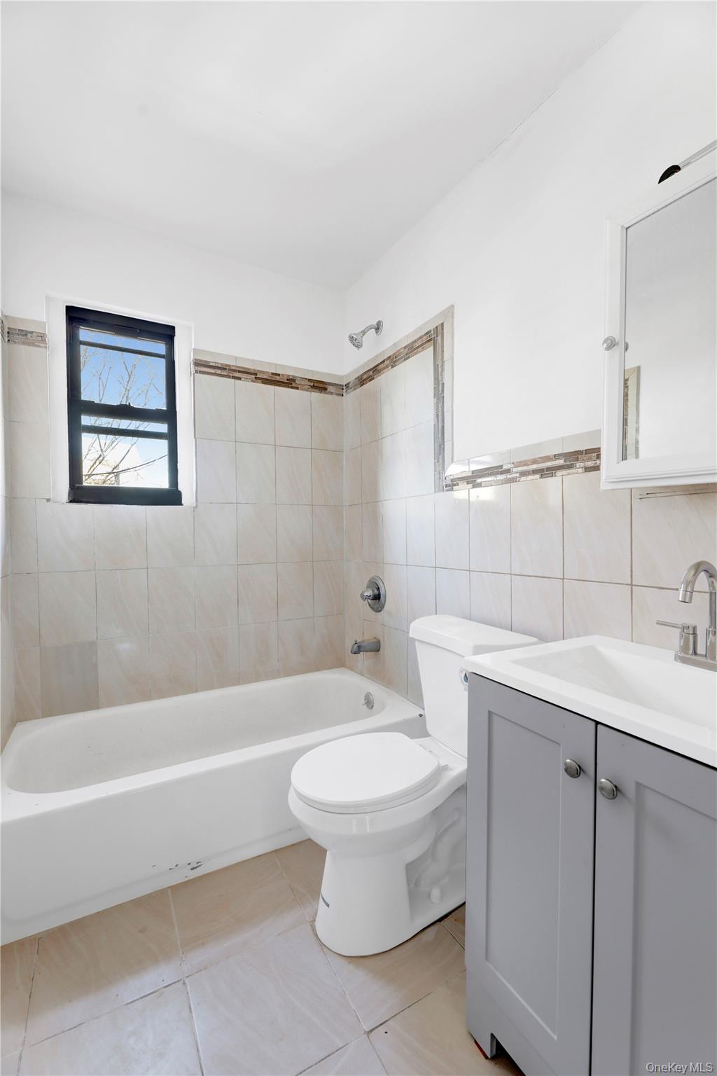 559 Cleveland Street Brooklyn, NY 11208 - Photo 23 of 34 Bathroom featuring vanity, tile walls, shower / tub combination, and light tile patterned floors