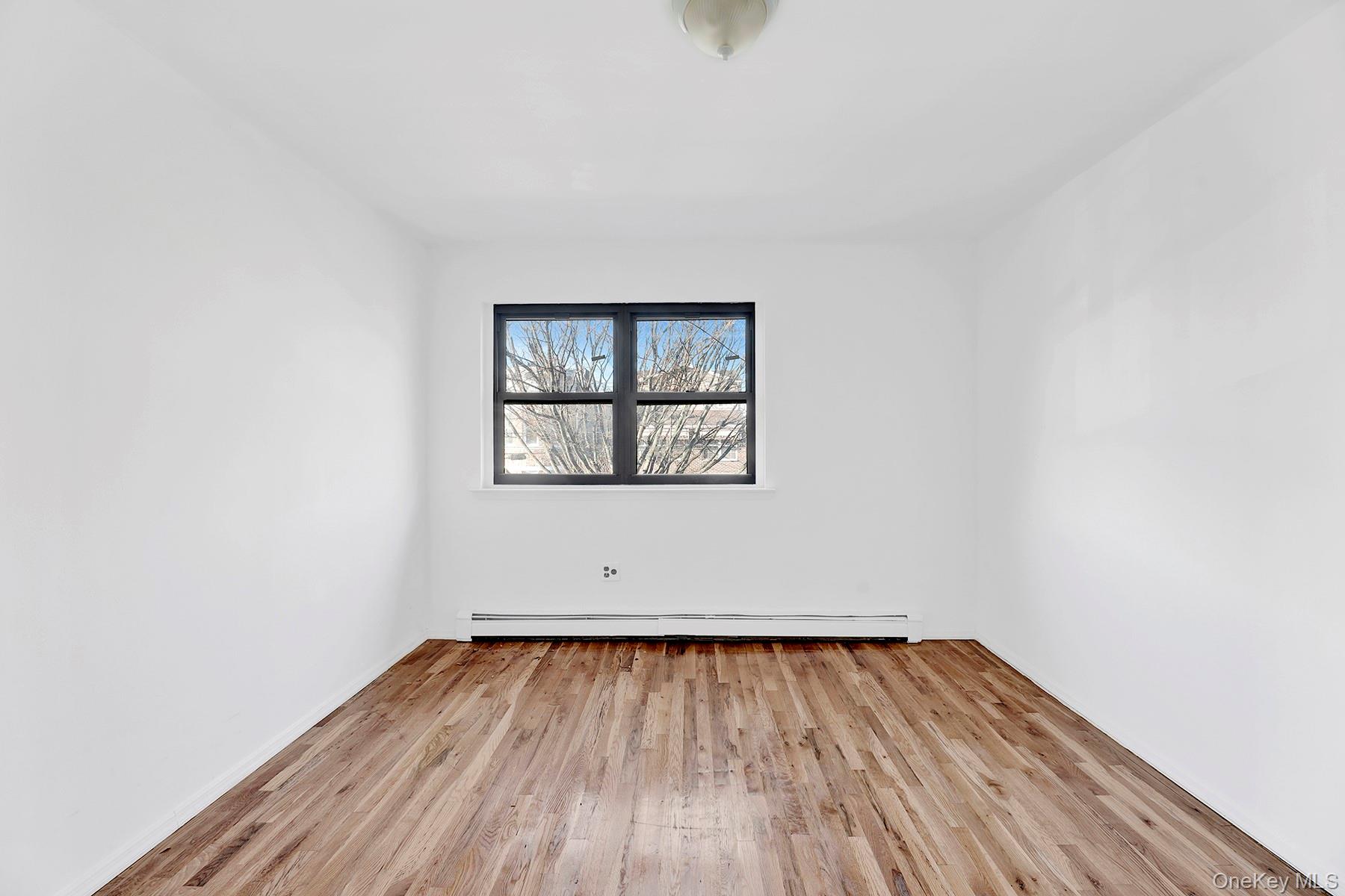 559 Cleveland Street Brooklyn, NY 11208 - Photo 27 of 34 Empty room with light wood-type flooring and a baseboard heating unit