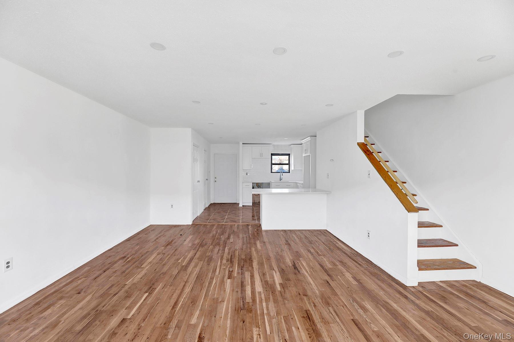 559 Cleveland Street Brooklyn, NY 11208 - Photo 3 of 34 Unfurnished living room featuring dark wood-type flooring and stairway
