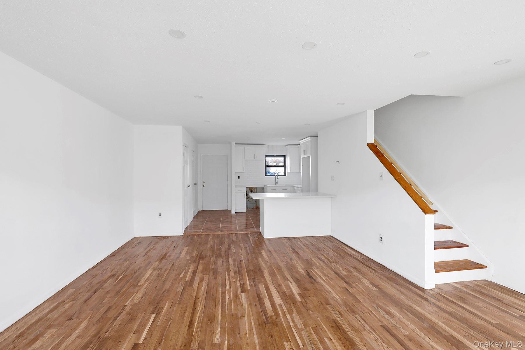 559 Cleveland Street Brooklyn, NY 11208 - Photo 5 of 34 Unfurnished living room with dark wood-style flooring and stairway
