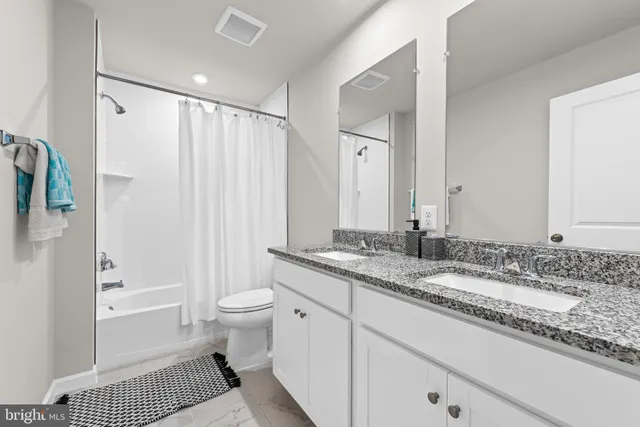 a bathroom with a granite countertop sink double vanity and a shower