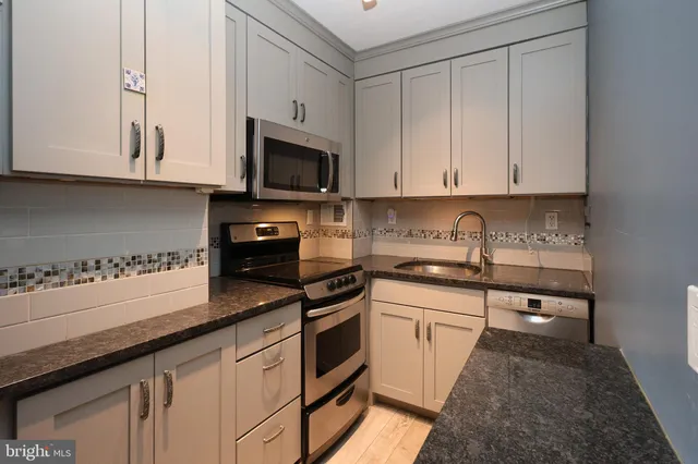 a kitchen with granite countertop white cabinets and stainless steel appliances