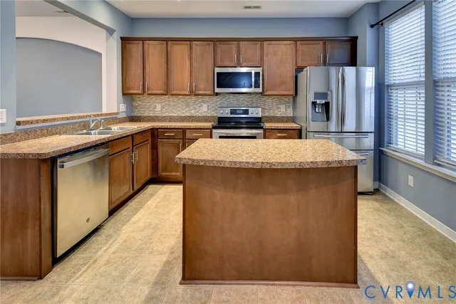 a kitchen with stainless steel appliances granite countertop a stove a sink and a microwave