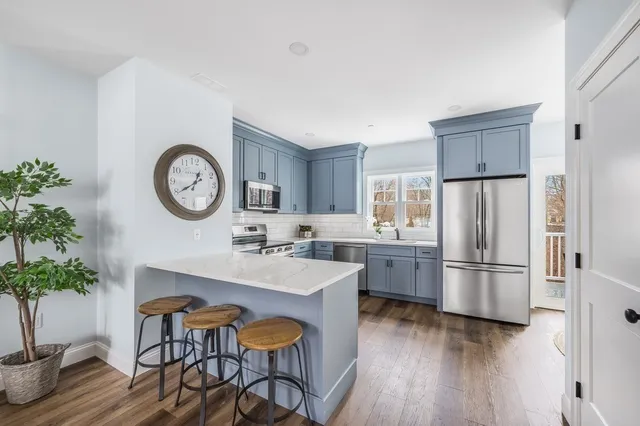 a kitchen with a refrigerator a microwave oven a sink and chairs