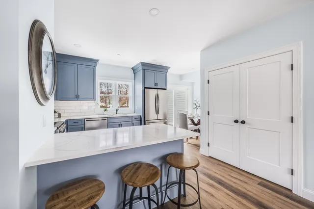 a large white kitchen with stainless steel appliances a counter space and wooden floor