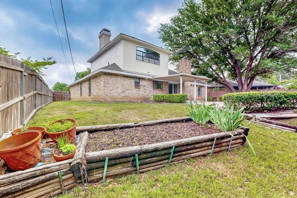 3965 Singleleaf Lane Fort Worth, TX 76133 - Photo 32 of 39 Expansive backyard featuring a wood fence, mature trees, a covered patio, and a raised garden bed
