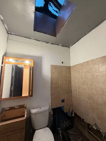 a bathroom with a granite countertop toilet sink and mirror
