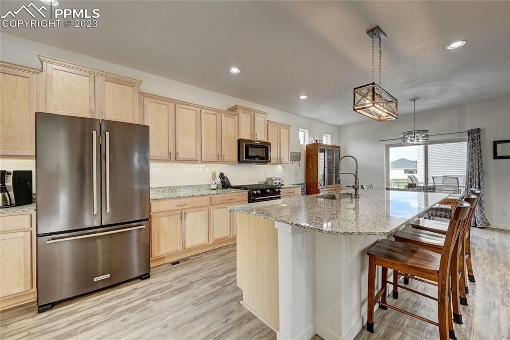 9642 Timberlake Loop Colorado Springs, CO 80927 - Photo 12 of 46 a kitchen with stainless steel appliances granite countertop a refrigerator a stove a sink a dining table and chairs with wooden floor