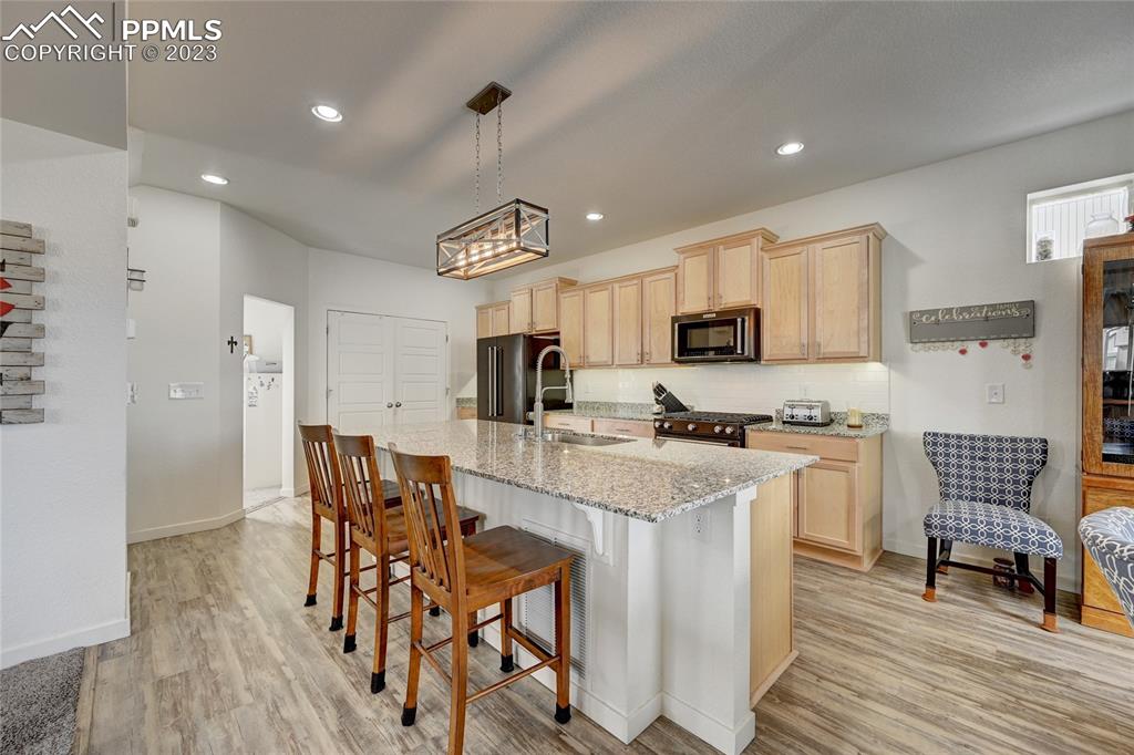 9642 Timberlake Loop Colorado Springs, CO 80927 - Photo 13 of 46 a kitchen with stainless steel appliances granite countertop a refrigerator a stove top oven a sink dishwasher a dining table and chairs with wooden floor