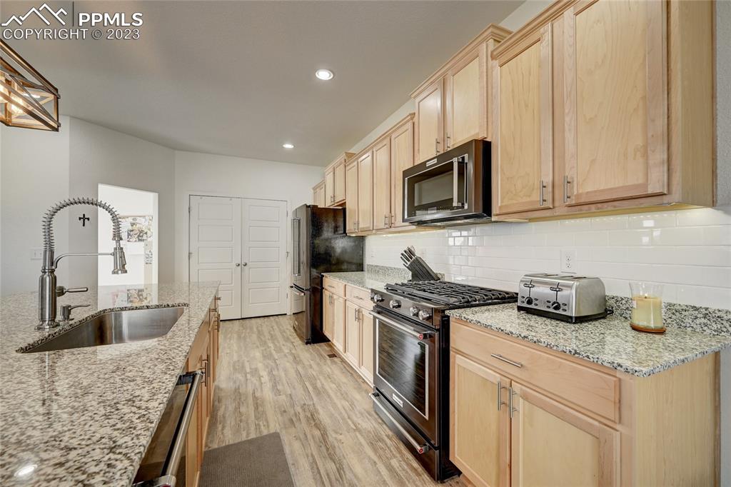 9642 Timberlake Loop Colorado Springs, CO 80927 - Photo 15 of 46 a kitchen with granite countertop a sink stove and refrigerator