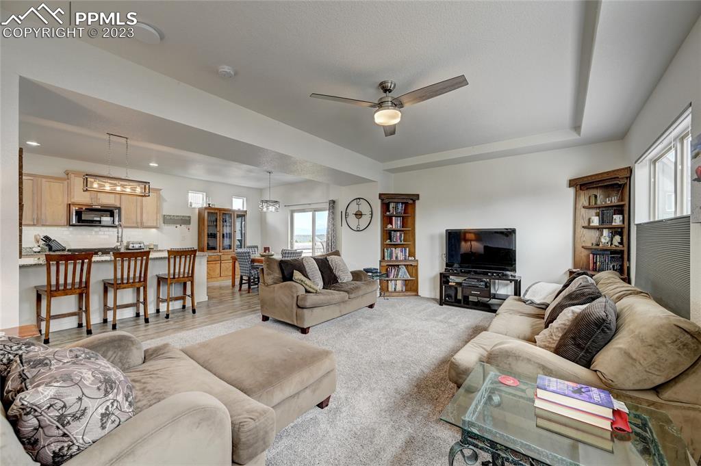 9642 Timberlake Loop Colorado Springs, CO 80927 - Photo 24 of 46 a living room with furniture and a flat screen tv with kitchen view