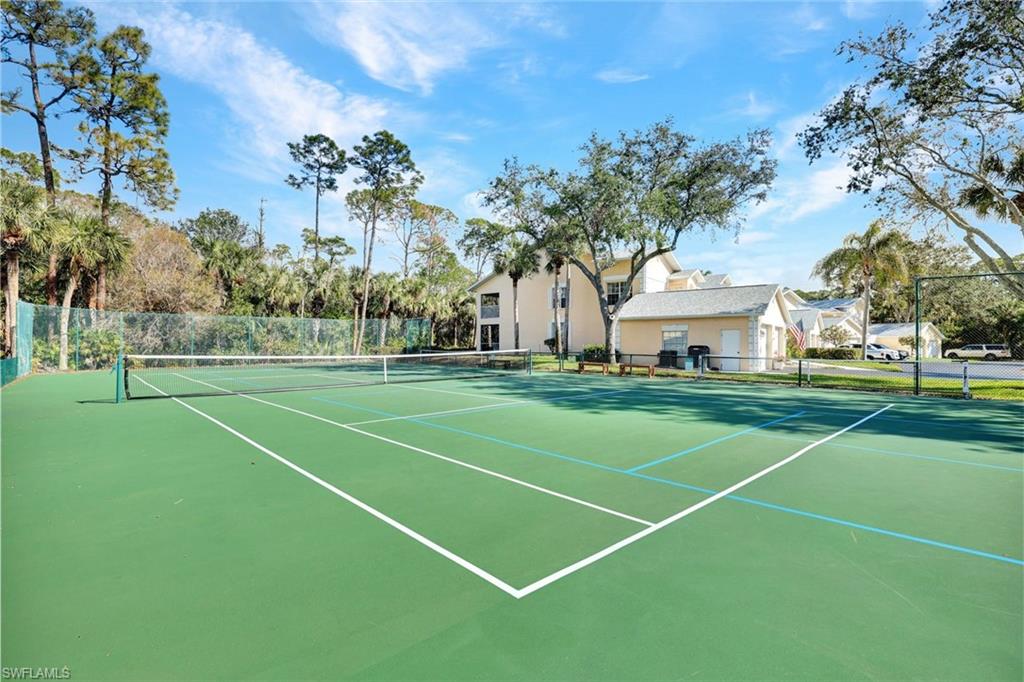437 Wiggins Lake Court, Unit 201 Naples, FL 34110 - Photo 22 of 24 a view of a tennis ground with large trees