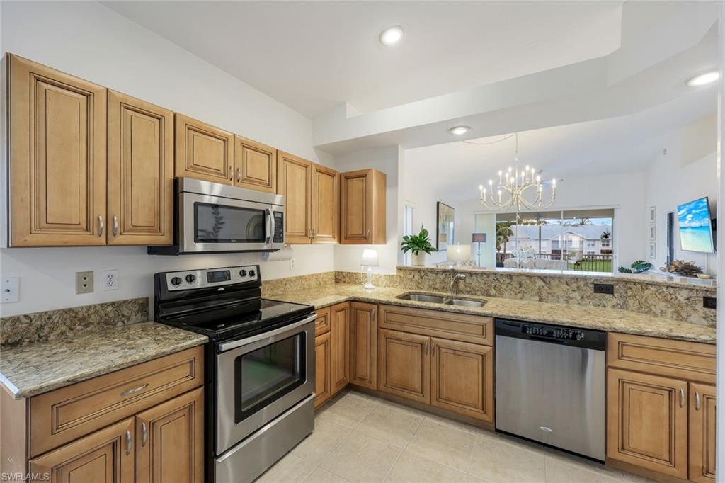 437 Wiggins Lake Court, Unit 201 Naples, FL 34110 - Photo 7 of 24 a kitchen with stainless steel appliances granite countertop a sink stove and microwave
