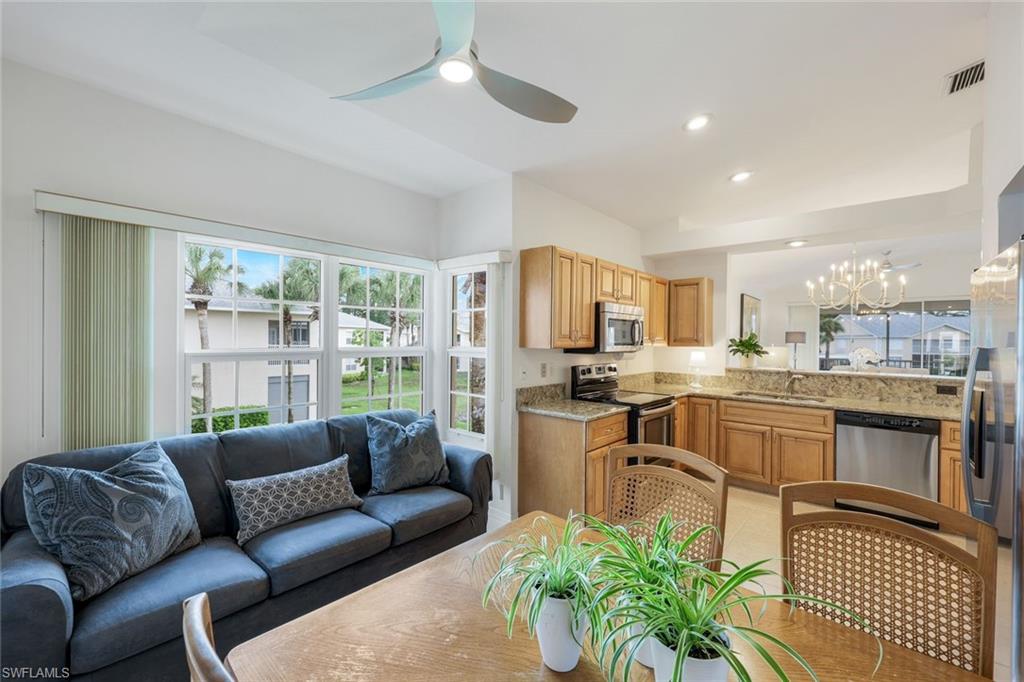 437 Wiggins Lake Court, Unit 201 Naples, FL 34110 - Photo 9 of 24 a living room with furniture a large window and a dining table