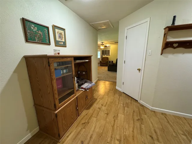 a view of a hallway with wooden floor and a bathroom