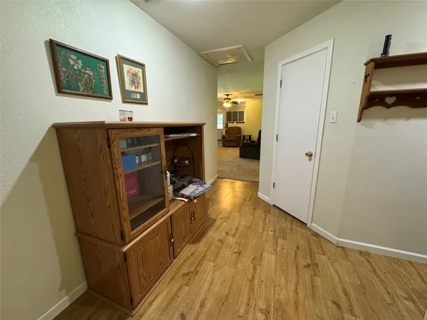 a view of a hallway with wooden floor and a bathroom