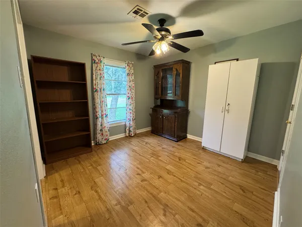 a view of empty room with wooden floor and fan