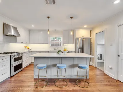 a kitchen with stainless steel appliances a dining table chairs stove and cabinets