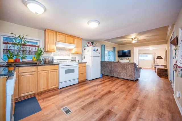 a kitchen with stainless steel appliances granite countertop a stove and white cabinets with wooden floor