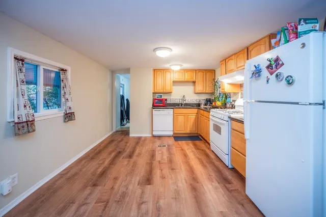 a kitchen with a refrigerator a stove top oven a sink and dishwasher with wooden floor