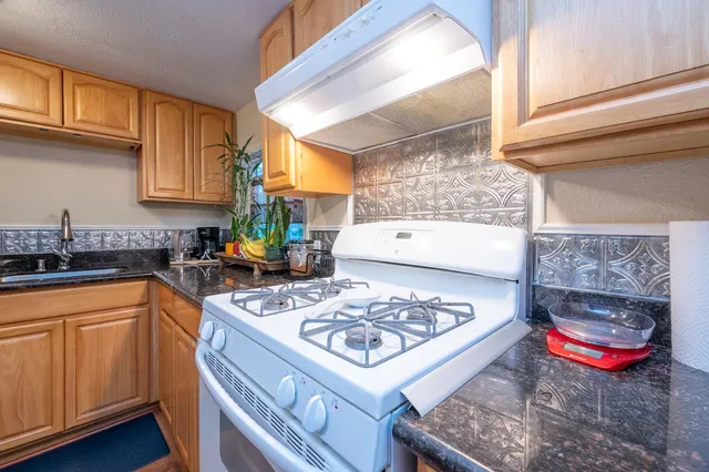 a kitchen with stainless steel appliances granite countertop a stove a sink and a microwave