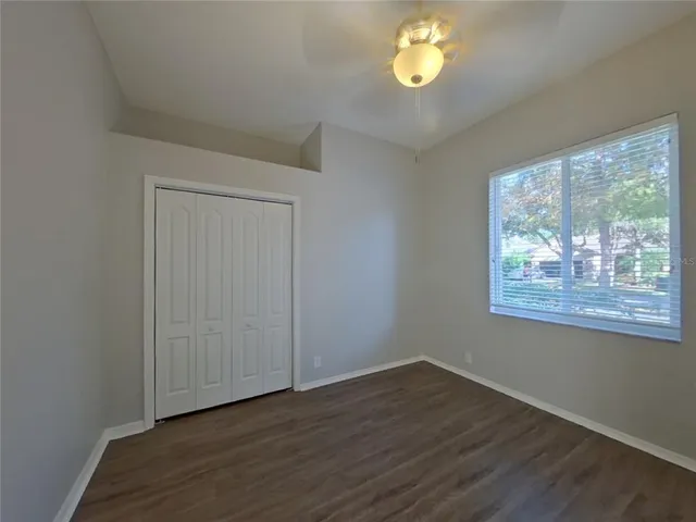 a view of an empty room with a window and wooden floor