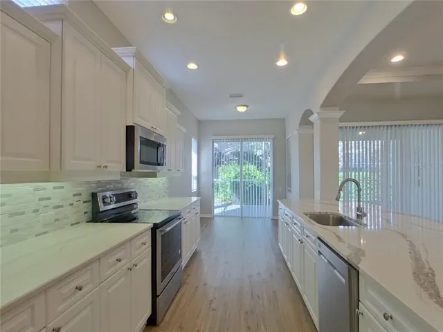 a kitchen with stainless steel appliances a sink a stove a microwave a sink and cabinets