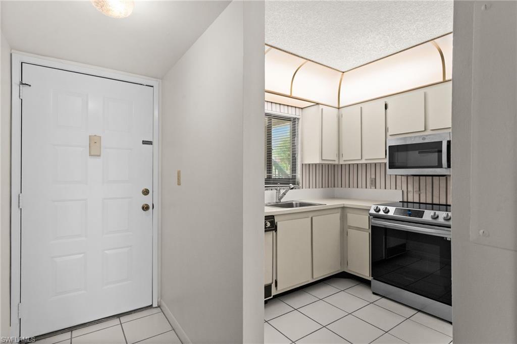 4251 27th Court Southwest, Unit 104 Naples, FL 34116 - Photo 12 of 22 a kitchen with stainless steel appliances a stove and a refrigerator