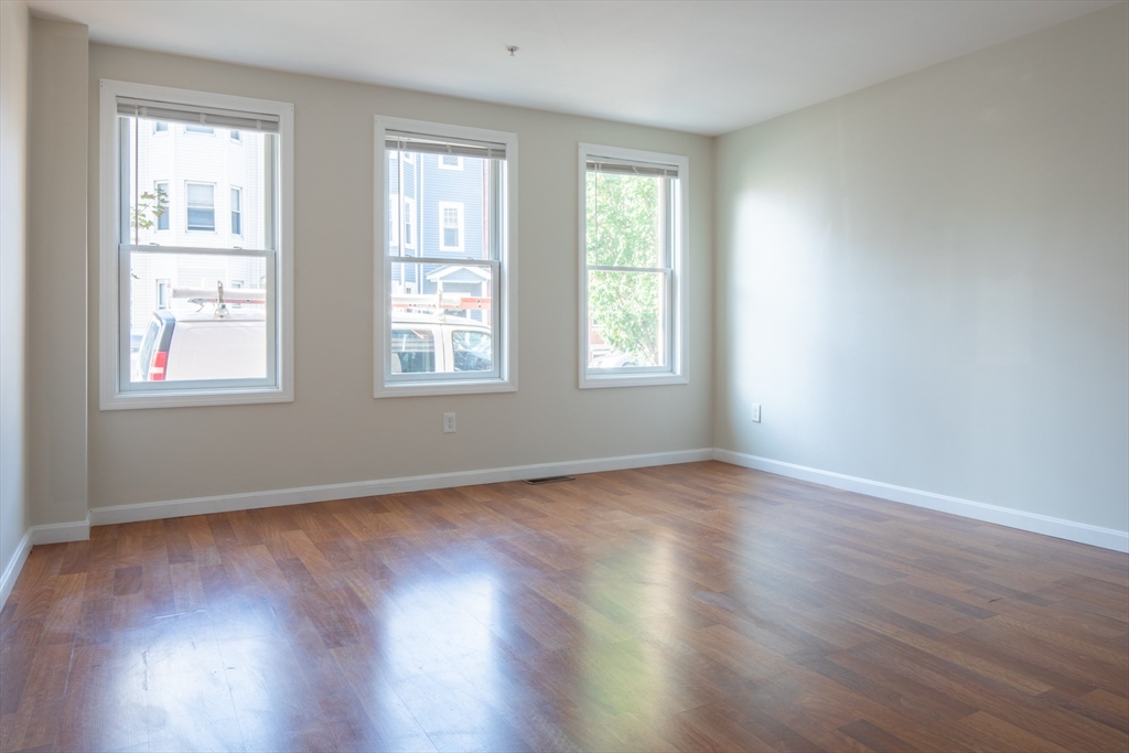 45 Chelsea Street, Unit 2 Boston, MA 02128 - Photo 7 of 10 an empty room with wooden floor and windows