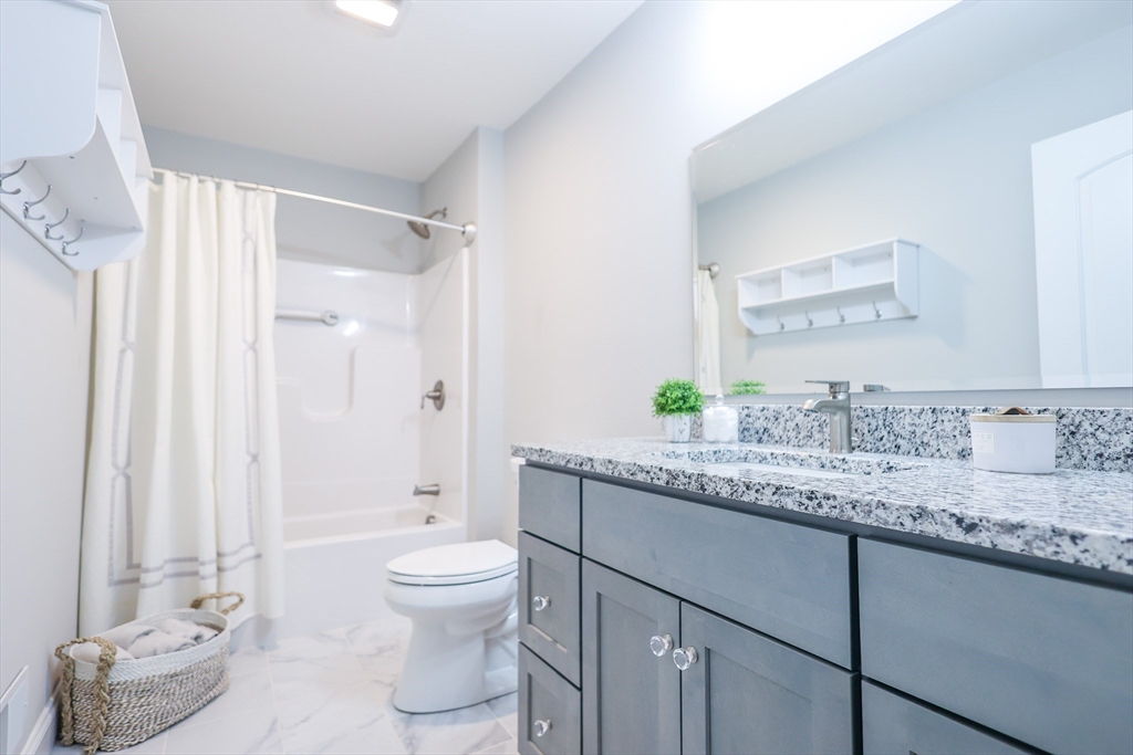 24 Del Ray Drive, Unit 25 Windham, NH 03087 - Photo 28 of 30 a bathroom with a granite countertop sink a toilet and a mirror