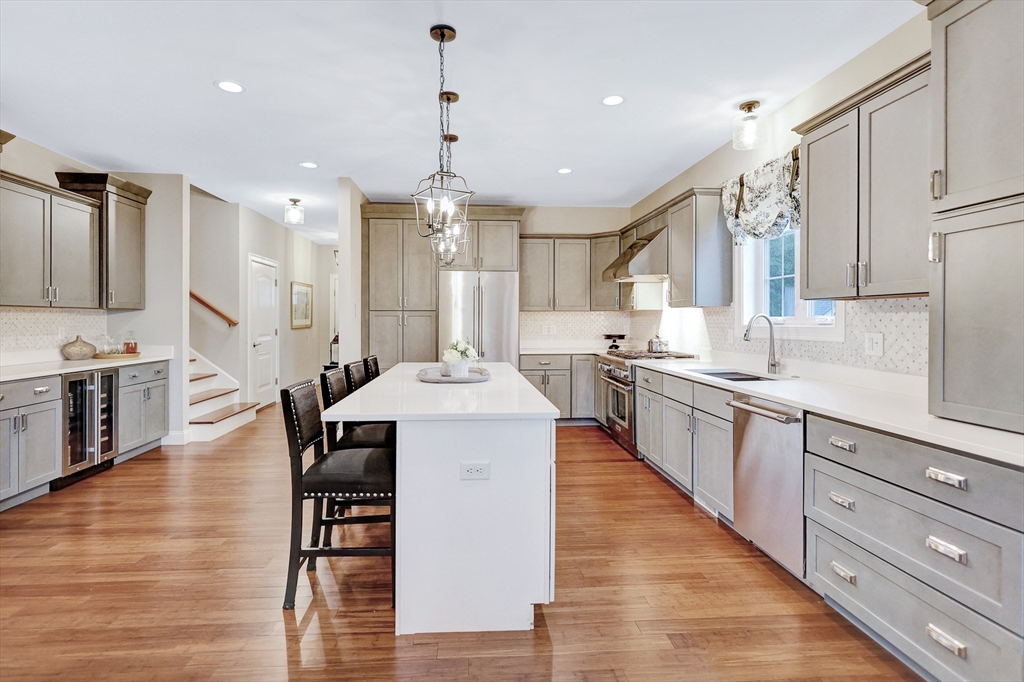 24 Del Ray Drive, Unit 25 Windham, NH 03087 - Photo 5 of 30 a kitchen with stainless steel appliances kitchen island granite countertop a stove a sink a refrigerator and white cabinets with wooden floor