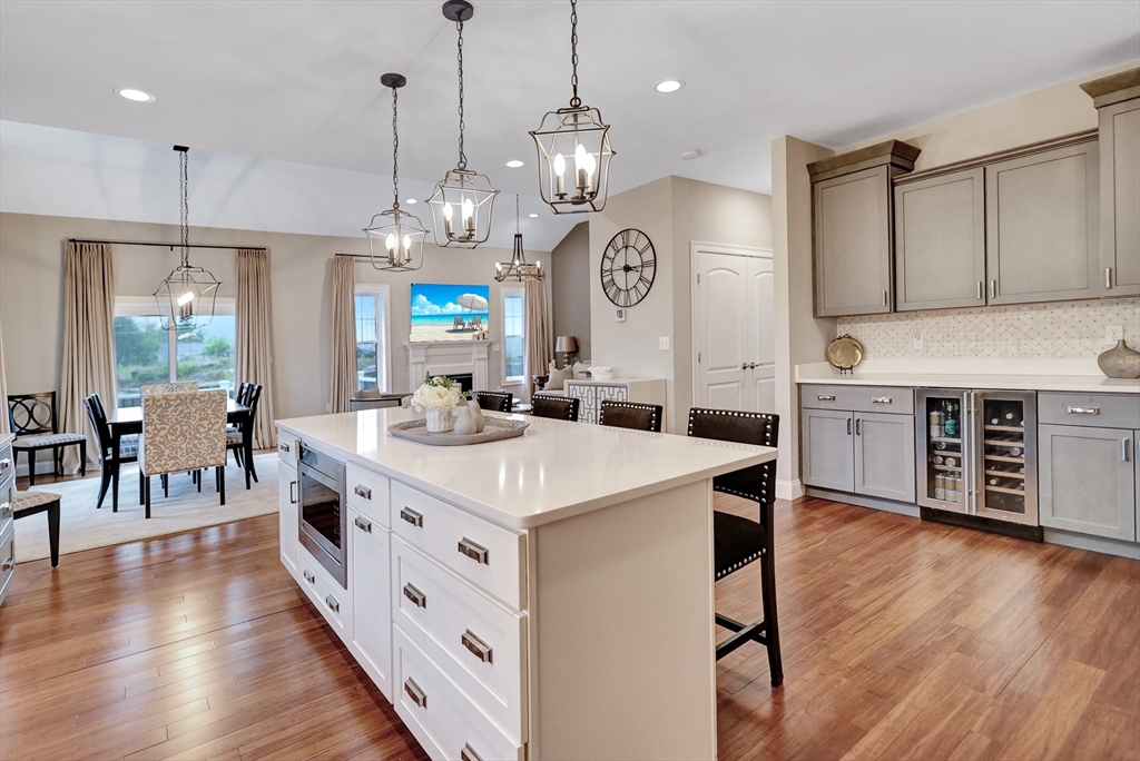 24 Del Ray Drive, Unit 25 Windham, NH 03087 - Photo 9 of 30 a large kitchen with a center island wooden floor stainless steel appliances and living room view