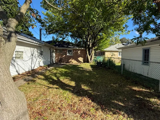 a view of a yard with plants and large trees