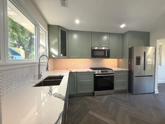 a kitchen with stainless steel appliances kitchen island granite countertop a sink stove and refrigerator
