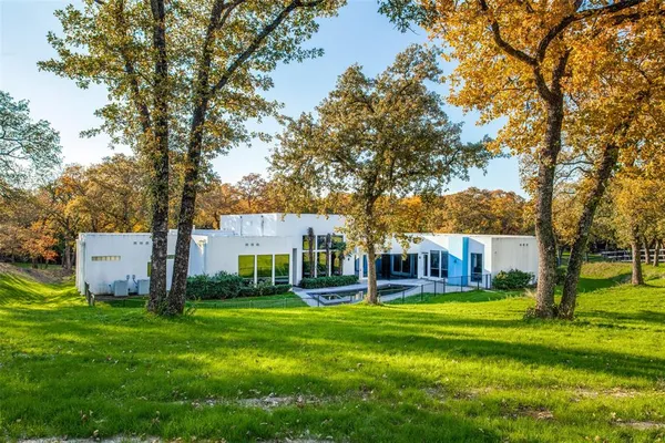 a view of a house with a big yard and large trees