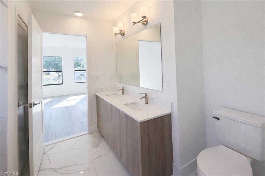 108 Indiana Place Lehigh Acres, FL 33936 - Photo 8 of 19 Bathroom featuring double vanity and light marble finish floors