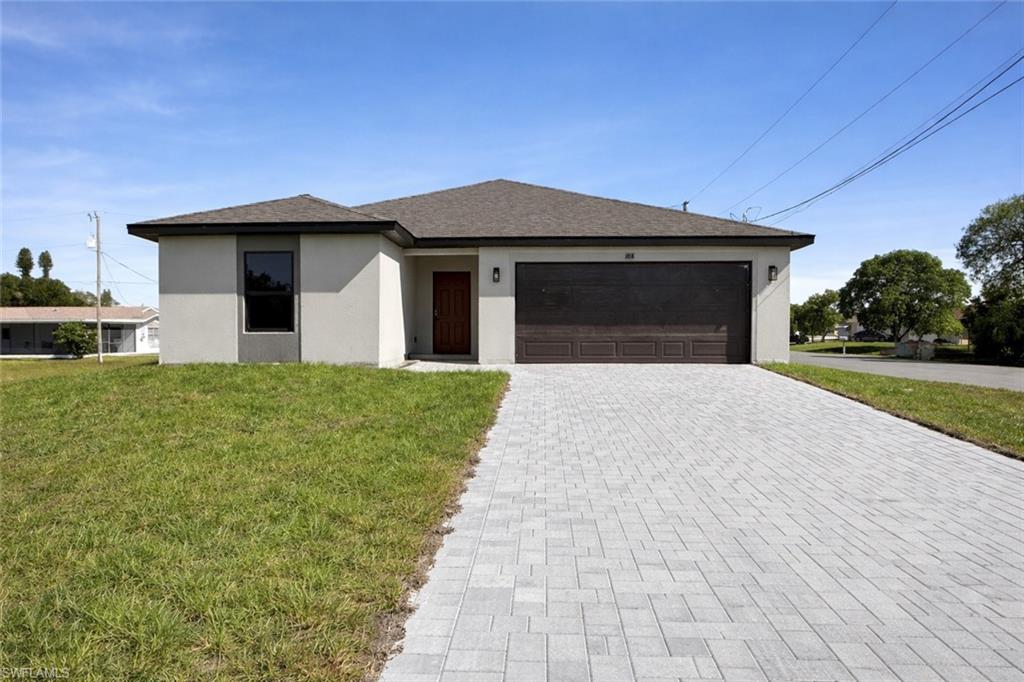 108 Indiana Place Lehigh Acres, FL 33936 - Photo 2 of 19 Single story home with stucco siding, a front yard, decorative driveway, a garage, and a shingled roof