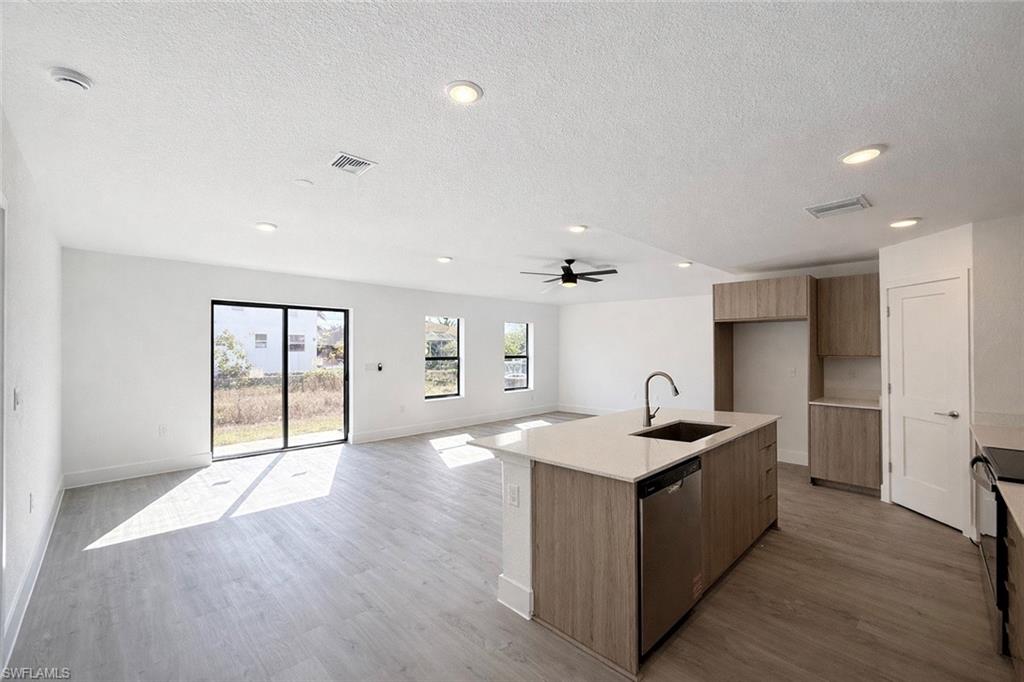 108 Indiana Place Lehigh Acres, FL 33936 - Photo 19 of 19 Kitchen with modern cabinets, a center island with sink, open floor plan, dishwasher, and a textured ceiling