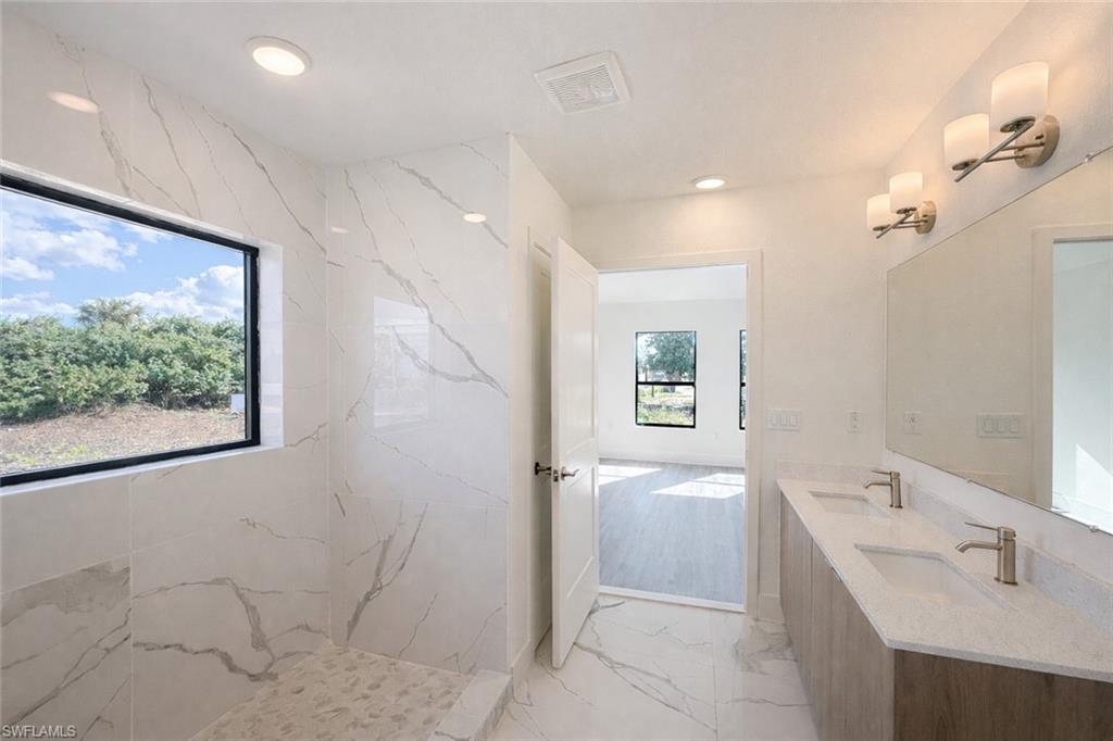 108 Indiana Place Lehigh Acres, FL 33936 - Photo 7 of 19 Full bathroom featuring light marble finish floors, double vanity, a marble finish shower, and recessed lighting