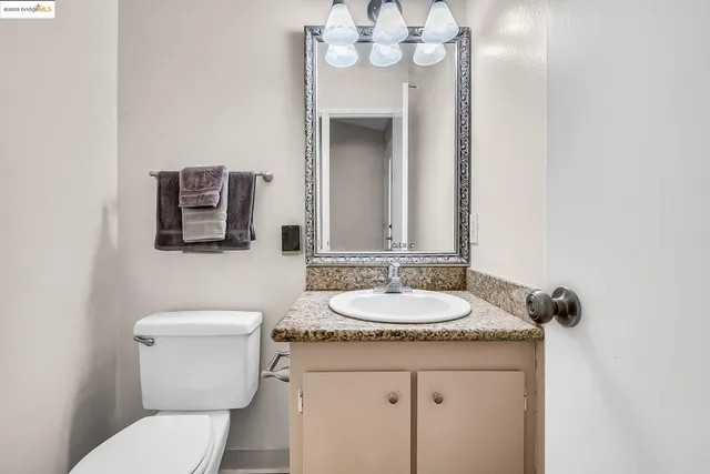 a bathroom with a granite countertop sink a toilet and a mirror