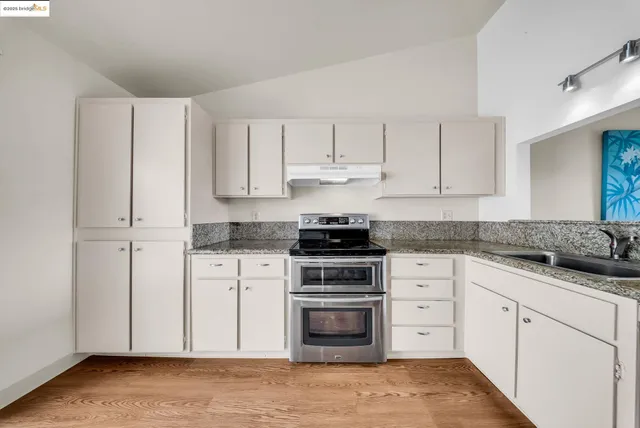 a kitchen with granite countertop white cabinets and stainless steel appliances