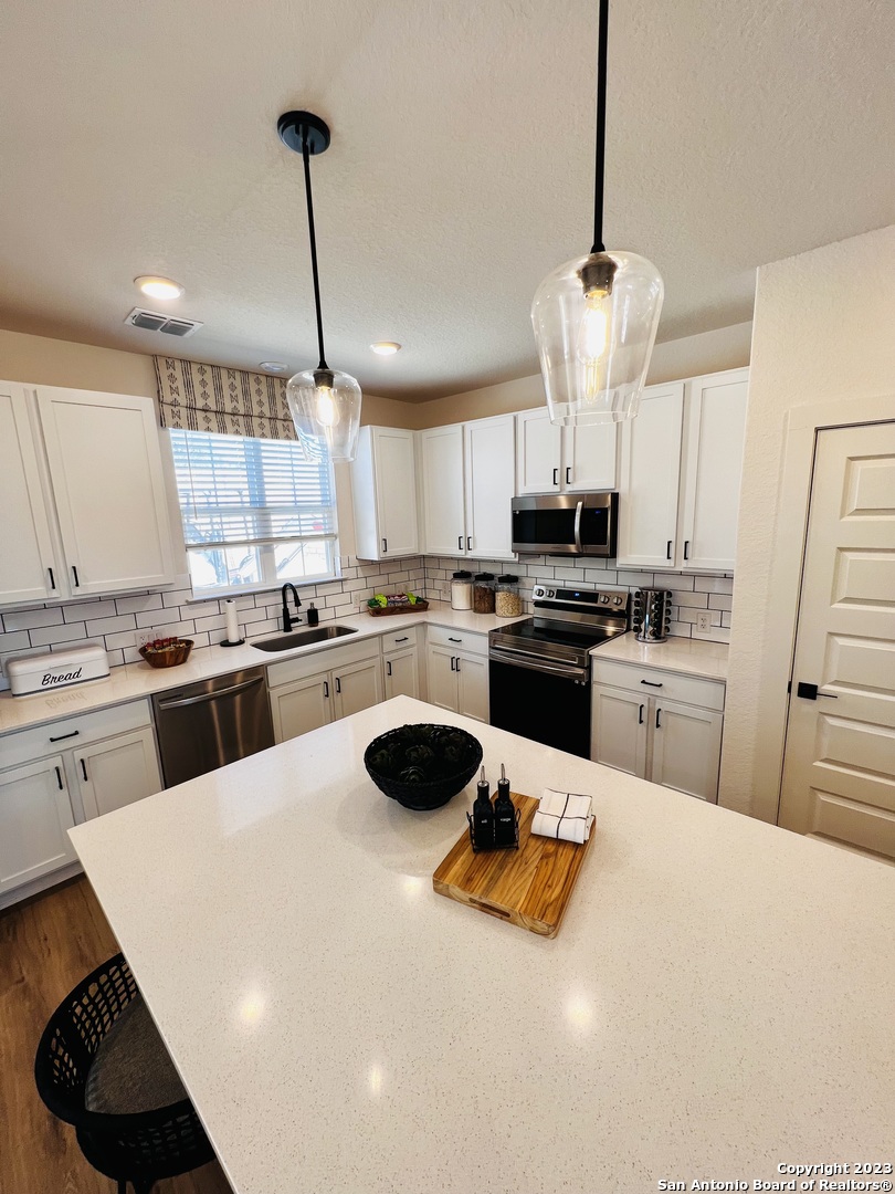 a kitchen with a sink stainless steel appliances and white cabinets