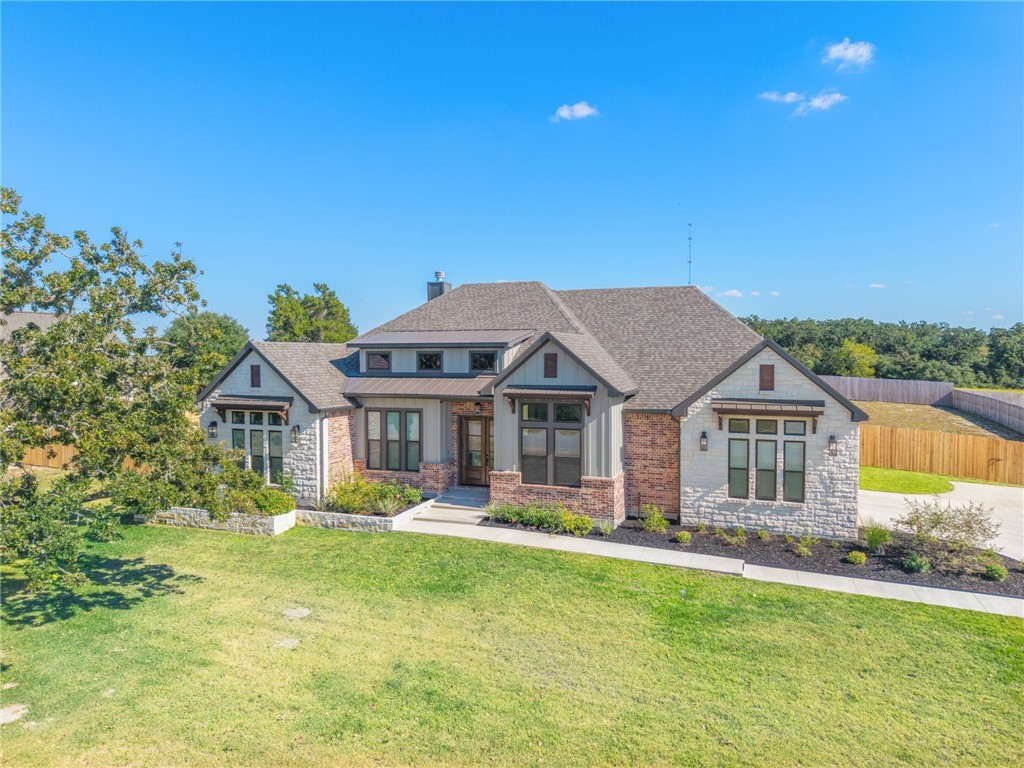 6652 Ridgeview Estates Lane Bryan, TX 77808 - Photo 1 of 1 View of front facade with stone siding, a chimney, a shingled roof, a standing seam roof, and a metal roof