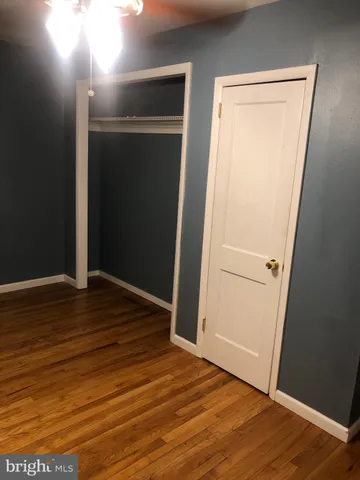 a view of an empty room with wooden floor and closet