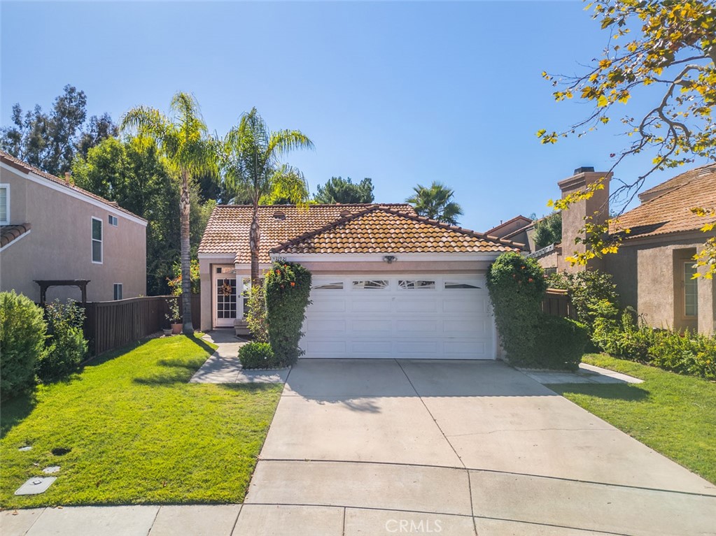 a view of a house with small yard plants and a large tree