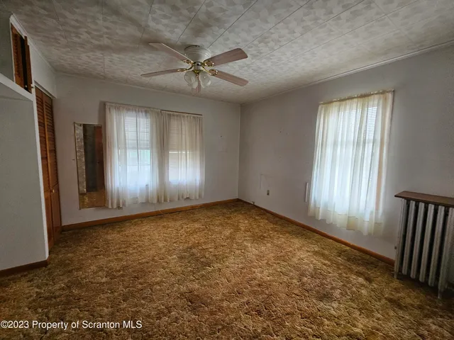 an empty room with windows & fan